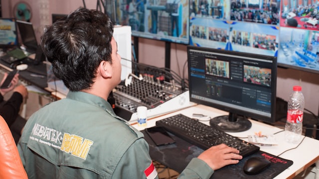Operador acompanhando vários monitores em uma sala de controle