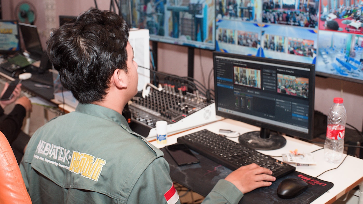 Operador acompanhando vários monitores em uma sala de controle